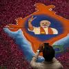 A supporter takes a picture of a map of India made of flowers with a picture of BJP leader Narendra Modi on it at the party's headquarters on May 16, 2014 in Ahmedabad, India.