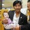 US Olympic skier Toby Dawson holds a baby in his arms as his South Korean father Kim Jae-Soo looks on while visiting a local adoption agency, Holt International Children's Service, in Seoul.