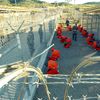 U.S. Military Police guard Taliban and al Qaeda detainees in orange jumpsuits January 11, 2002 in a holding area at Camp X-Ray at Naval Base Guantanamo Bay, Cuba.