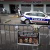 June 26, 2015. Outside the Hypercacher kosher supermarket in Paris. A police car parked behind a metal barrier with a sign featuring the portraits of the four victims of a bloody hostage drama.