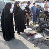 Iraqi onlookers gather on July 16, 2014 around a burnt motorcycle at the scene of an explosion that took place the previous night in Sadr City, one of Baghdad's northern Shiite-majority districts.
