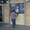 A man puts a wooden board over a window of the Student Union on the University of California, Berkeley campus in Berkeley, Calif. 