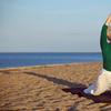 Senior woman practicing yoga poses on the sandy beach. 