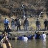 Dozens of protestors demonstrating against the expansion of the Dakota Access Pipeline wade in cold creek waters confronting local police, as remnants of pepper spray waft over the crowd near Cannon B