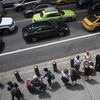 In this Wednesday, Aug. 1, 2018 photo, a ride-hailing car, a yellow cab and a green cab make their way across 42nd Street as passengers wait in line at a taxi stand outside Grand Central Terminal