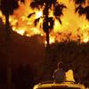 King Bass, 6, left, sits and watches the Holy Fire burn from on top of his parents' car as his sister Princess, 5, rests her head on his shoulder Thursday night, Aug. 9, 2018 in Lake Elsinore, Calif.