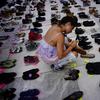 A woman places one of the hundreds of shoes in memory of those killed by Hurricane Maria in front of the Puerto Rico Capitol, in San Juan, Friday, June 1, 2018. 