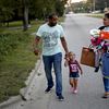 Jose Perez-Santiago, left, and Rosemary Acevedo-Gonzalez, walk with their daughter Jordalis, 2, after retrieving her clothing upon returning to their home for the first time since it was flooded