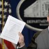 Deputy Attorney General James Cole holds up a list of guidelines during a news conference at the Justice Department in Washington, Wednesday, April 23, 2014. Cole announced the new standards that will