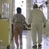  In this Wednesday, April 9, 2008 file photo, Debbie Coluter, a certified nursing assistant, holds the hand of an elderly inmate with Alzheimer's disease, as she helps him to his cell at the Calif
