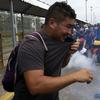 Men attempt to grab a tear gas canister thrown by the Mexican Federal Police, after Central American migrants rushed the gate at the border crossing in Ciudad Hidalgo, Mexico, Friday, Oct. 19, 2018. 