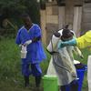 In this photo taken Sunday, Sept 9, 2018, a health worker sprays disinfectant on his colleague after working at an Ebola treatment centre in Beni, Eastern Congo. 