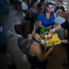In this Sept. 7, 2018 photo, a woman with her child receives free diapers and shower gel, as she and others line up for food and other donated staples from the MARC