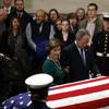 Former President George W. Bush and former first lady Laura Bush pause in front of the flag-draped casket of former President George H.W. Bush as he lies in state in the Capitol's Rotunda in Washingto