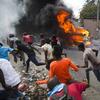 Demonstrators run away from police who are shooting in their direction, as a car burns during a protest demanding the resignation of Haitian President Jovenel Moise in Port-au-Prince, Haiti