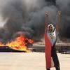 A protester flashes the victory sign in front of burning tires and debris on road 60, near Khartoum's army headquarters, in Khartoum, Sudan, Monday, June 3, 2019. 