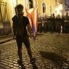 A demonstrator with a Puerto Rican flag stands in front of the police during clashes in San Juan, Puerto Rico, Wednesday, July 17, 2019.