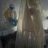 Health workers wearing protective gear check on a patient isolated in a plastic cube at an Ebola treatment center in Beni, Congo. 