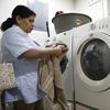 In this Dec. 14, 2018 photo, domestic worker Rocio Campos, removes a towel from the dryer, in Mexico City.