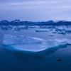 In this Aug. 15, 2019, photo, a boat navigates at night next to large icebergs near the town of Kulusuk, in eastern Greenland.