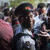 A police officer stands guard as Haitian migrants waiting to get food distributed by humanitarian organizations in Nassau, Bahamas, Sunday, Sept. 29, 2019. 