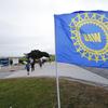 In this Sept. 30, 2019, file photo a UAW flag flies near strikers outside the General Motors Orion Assembly plant in Orion Township, Mich.