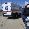 A United States Postal worker makes a delivery with gloves and a mask in Warren, Mich., Thursday, April 2, 2020. 