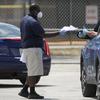 A worker gets a thumbs up as he hands out paper unemployment applications, Tuesday, April 7, 2020, at Babcock Park in Hialeah, Fla. 