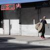 A homeless man carrying his bedding walks past shuttered businesses during the new coronavirus pandemic, Thursday, May 7, 2020, in Miami. 