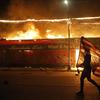 A protester carries a U.S. flag upside down, a sign of distress, next to a burning building Thursday, May 28, 2020, in Minneapolis. Protests over the death of George Floyd.