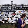A woman passes a fence outside Brooklyn's Green-Wood Cemetery adorned with tributes to victims of COVID-19, Thursday, May 28, 2020, in New York. 