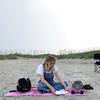 Laura Bratton, who has been sober for two and a half years, sits on the beach reading a book as she waits for a 12-step meeting to start in Wilmington, North Carolina.