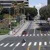 A man crosses a street on a wheelchair Friday, March 20, 2020, in downtown Los Angeles.