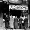 In this circa 1911 photo made available by the Library of Congress, men look at materials posted in the window of the National Anti-Suffrage Association headquarters in the United States.