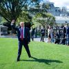trump walking on a lawn, waving at people and press