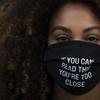 In this Monday, Dec. 7, 2020, file photo, Daisha Graf, 34, pauses for photos wearing a face mask with a message that reads 'If you can read this, you're too close,' in Los Angeles. 