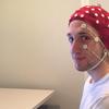 a man in a red beanie-like cap that has various electrodes on it to monitor brain signals