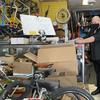A man dressed in black stands in a bike shop crowded with bikes