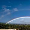 a full double rainbow stretching across a blue sky