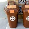 brown composting bins sit side-by-side on a sidewalk