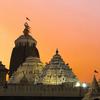 pyramid-like set of three temples - one with a flag flying int the breeze above - against a pinkish sunset