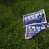 Two damaged Trump/Pence campaign signs lie on grass