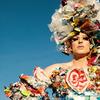 a white drag queen posing outside wearing a dress made up of pieces of trash