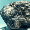 a porous meteorite that's mostly dark grey, but has some tiny shiny spots