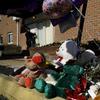 Stuffed bears and a balloon are lined up on a sidewalk as a memorial.