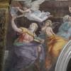 Two women and three cherub-like angels are painted over an arch.