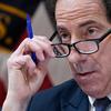 Congressman Jamie Raskin glances over his eyeglasses while holding a blue pen.