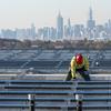 Framed by the Manhattan skyline, electricians with IBEW Local 3 install solar panels on top of the Terminal B garage at LaGuardia Airport, Nov. 9, 2021, in the Queens borough of New York. 