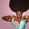 Close-up portrait of Bob the Drag Queen in a blue gown with pink highlights, matching makeup, and large Afro. She looks into the camera and holds her hands under her chin.