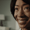 Betty Gabriel as Georgina in Jordan Peele's Get Out looks up at the left corner of the screen almost crying while smiling
